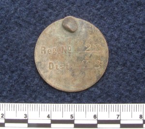 Circular dog tag stamped with registration number 28 and district 78