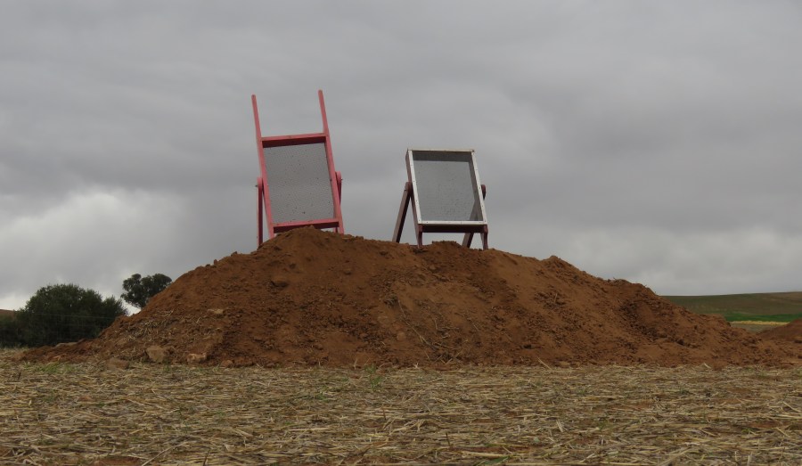 Two large sieves on top of a pile of sieved dirt.
