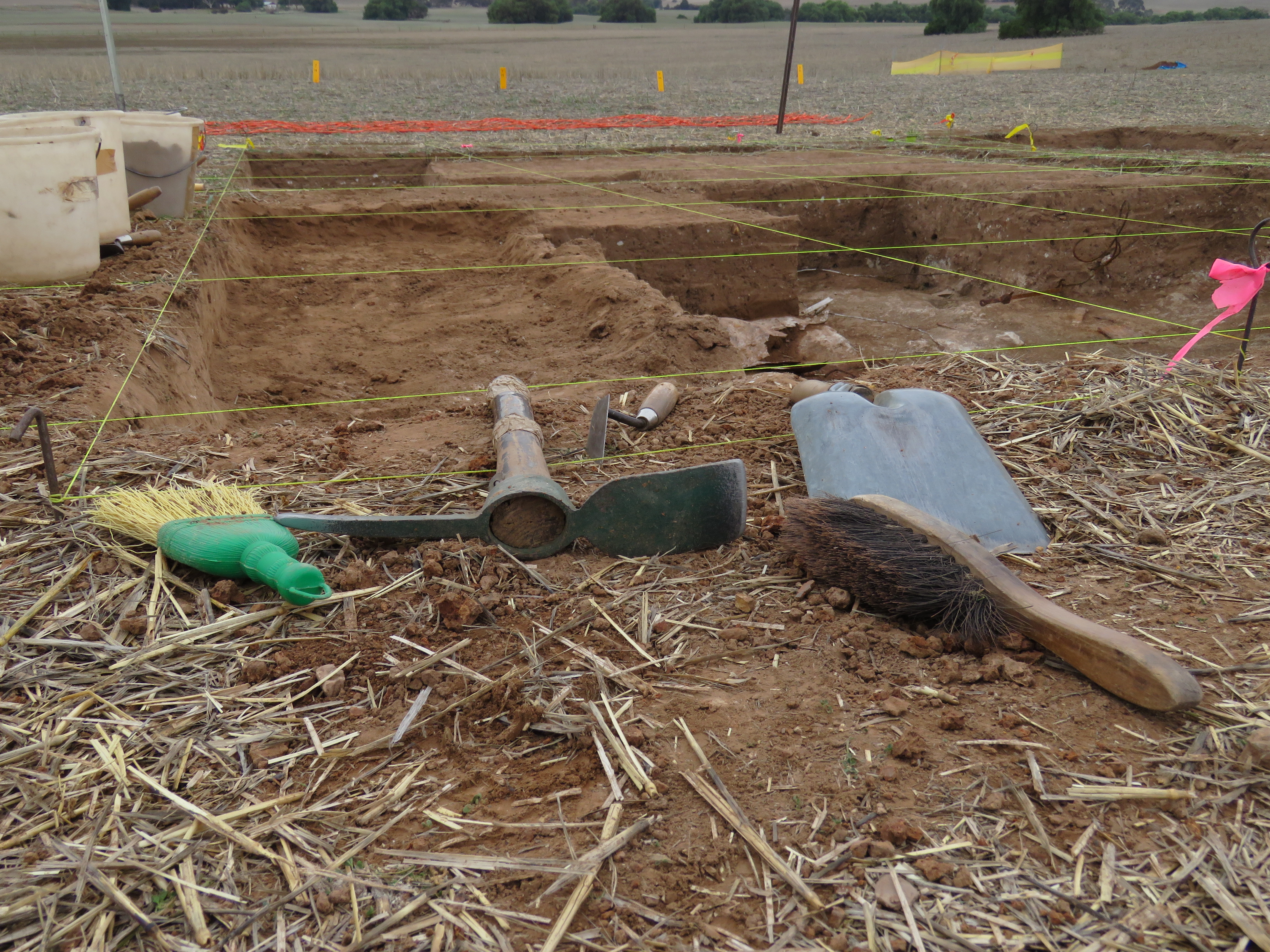 Brush, mattock and shovel at edge of trench.